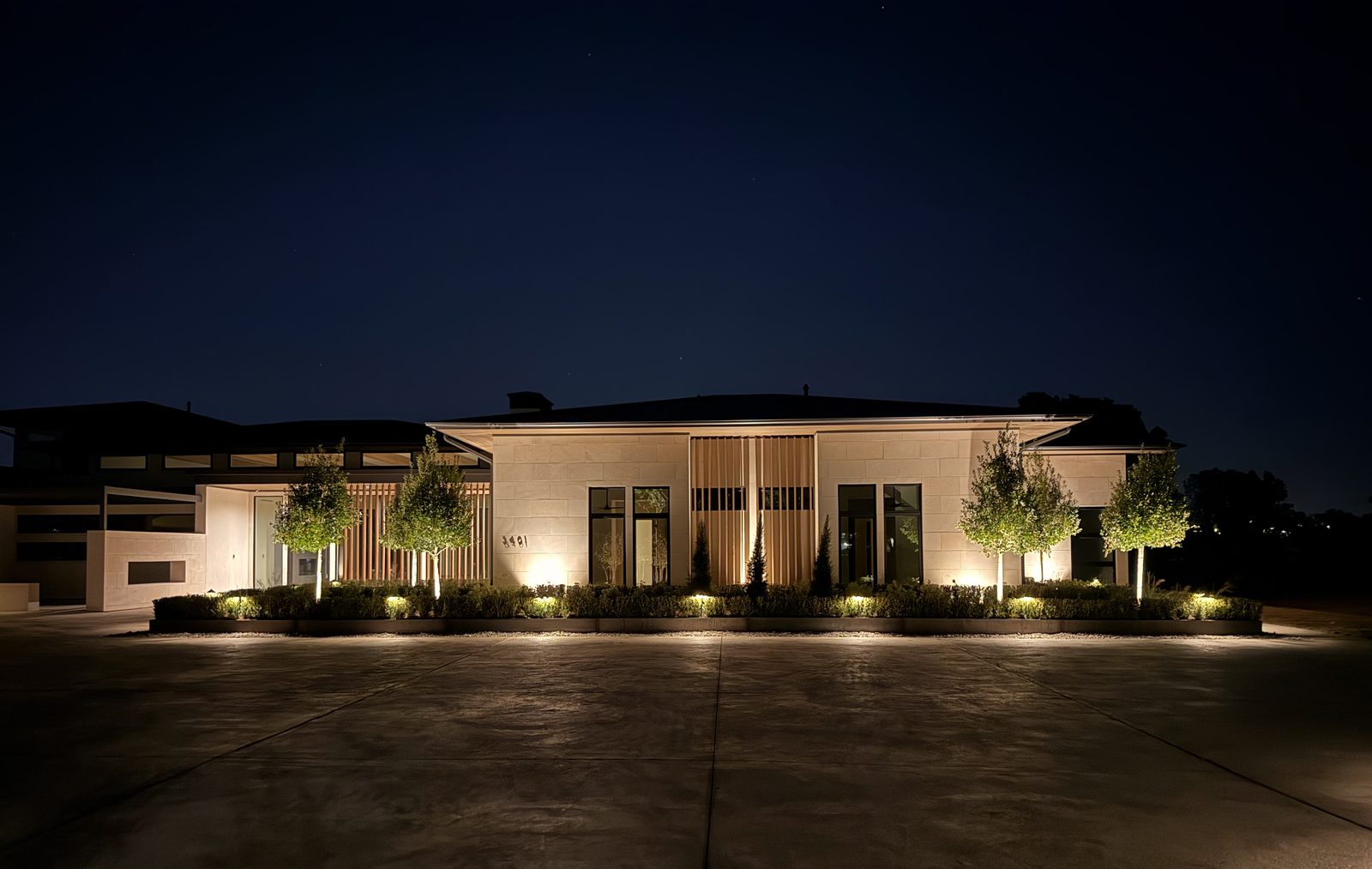 Modern single storey home at dusk with ground level uplighting washing the front elevation